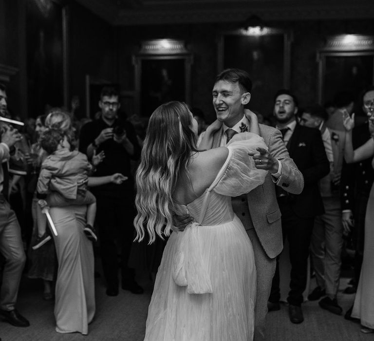 Bride in whimsical wedding dress with puff sleeves dances with the groom on their wedding day 