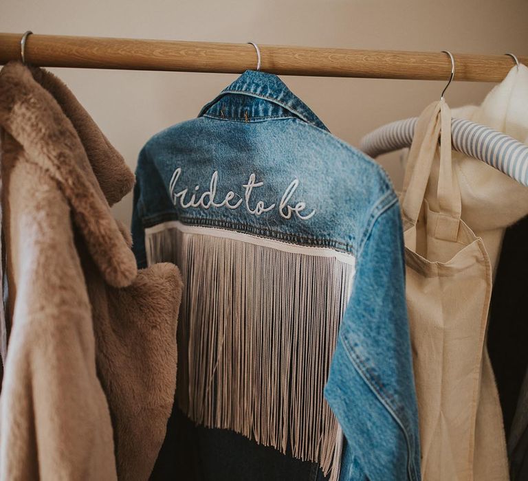 Bride's blue denim jacket with white tassels and cursive font spelling out 'bride to be' 