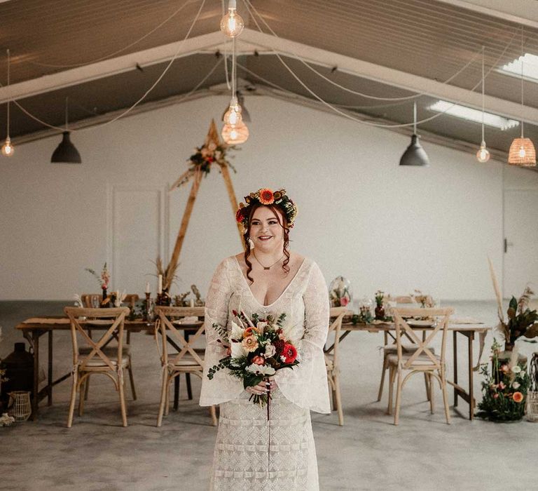 Bride in v-neck long bell sleeve boho wedding dress holding natural earthy toned garden rose, pampas grass, dried flower and foliage bridal bouquet in The Barn at Avington