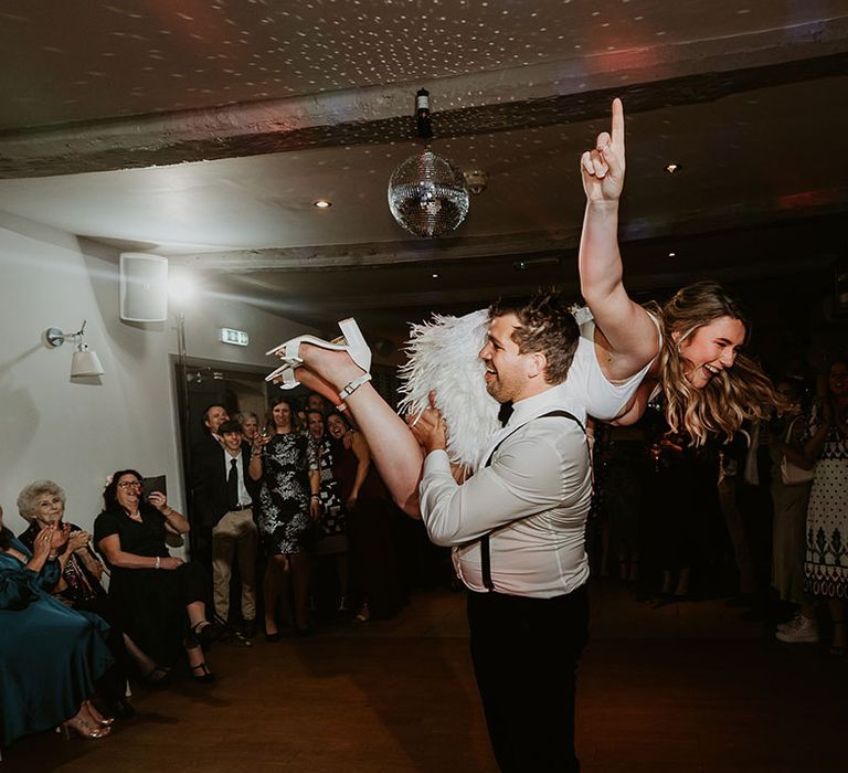 Bride in tassel short skirt wedding reception outfit being lifted dancing with the groom 