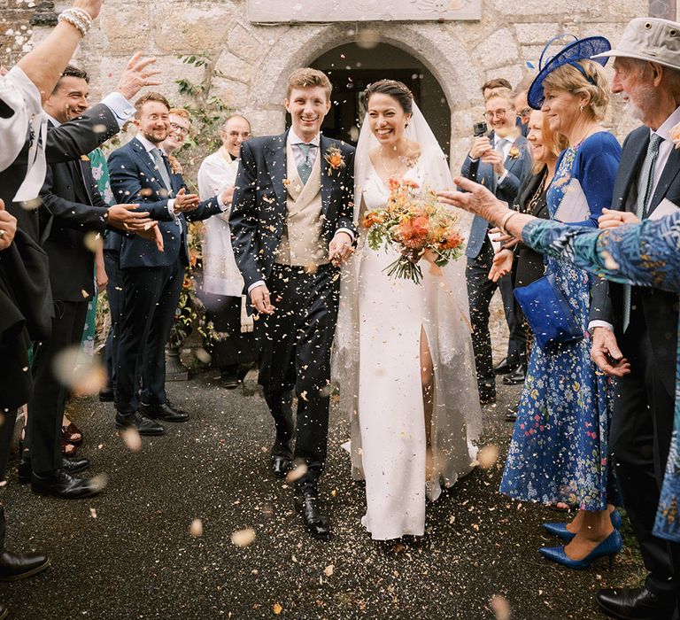 The bride and groom exit from their church ceremony to confetti 