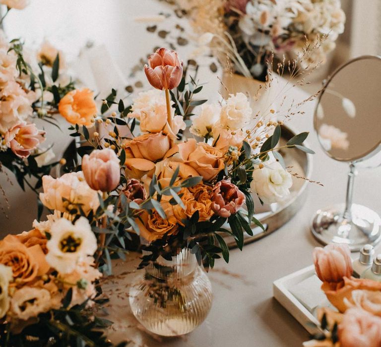 Blush and orange garden roses, poppies and carnations, dried flowers and eucalyptus wedding bouquets in glass vases 