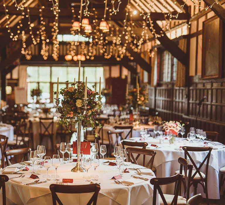 Traditional Ramster Hall wedding in Surrey decorated for autumn wedding with fairy lights and tall floral centrepieces 