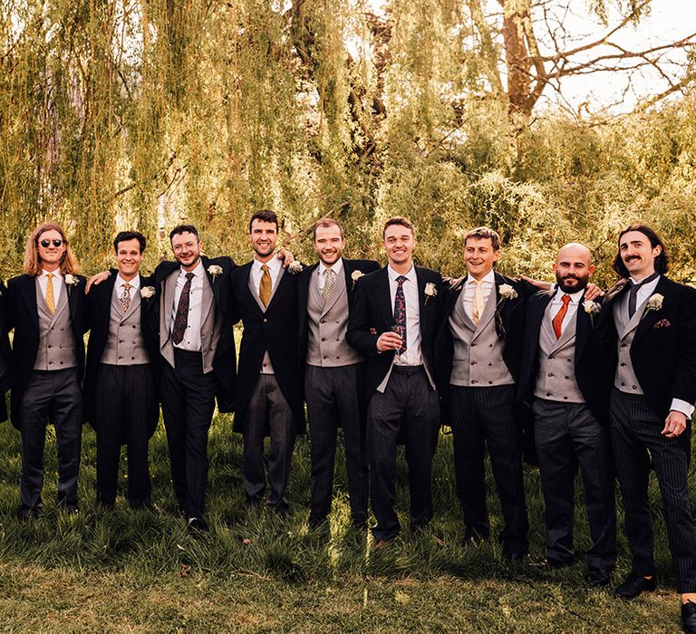 Groomsmen in mismatched morning suits with different coloured ties for spring wedding 