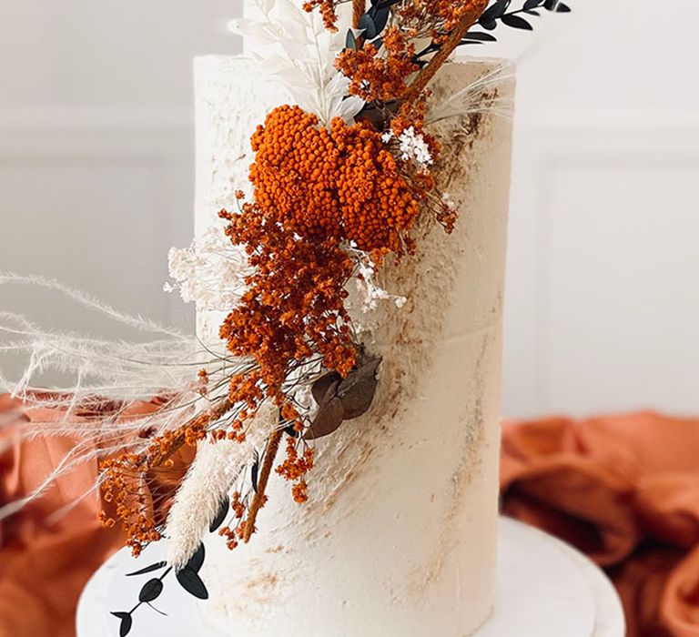 White iced wedding cake with red wedding flowers decorated by Bloom Bakehouse 