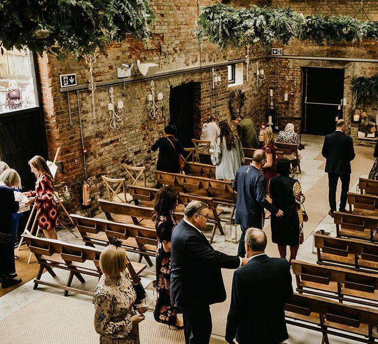 The Botley Hill Barn in Surrey wedding venue with guests taking their seats for the ceremony 