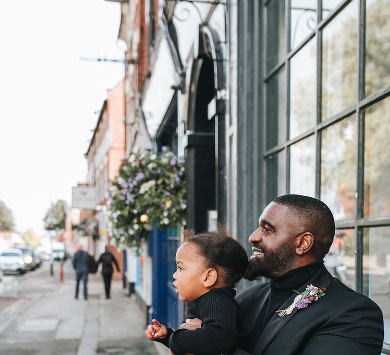 The page boy and groom in matching black wedding outfits together 