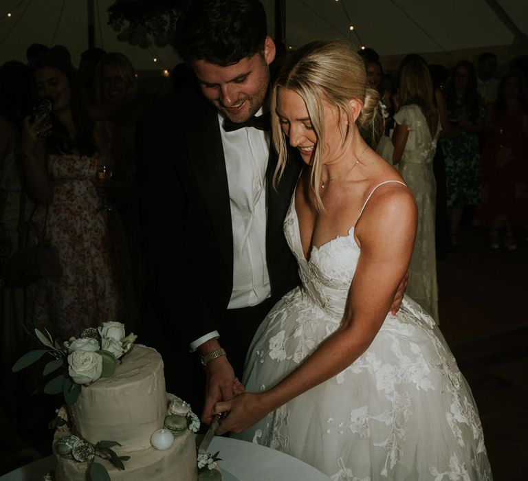 The bride and groom cut into their three tier simplistic green and white wedding cake 