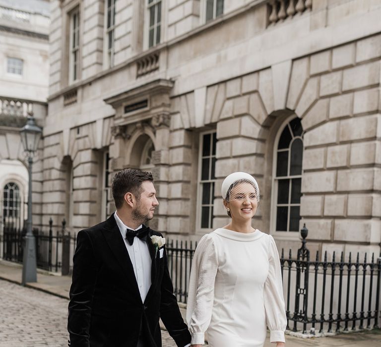 Groom in black tuxedo with the bride walking hand in hand with the bride at the wedding 