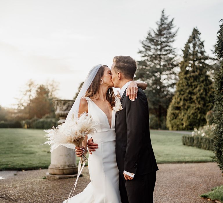 Romantic couple portrait with the bride and groom sharing a kiss together at their winter wedding 