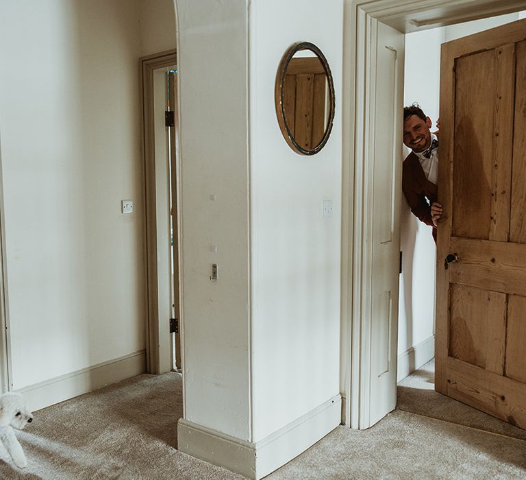 The two grooms peek around their bedroom doors as they get ready for the wedding separately 