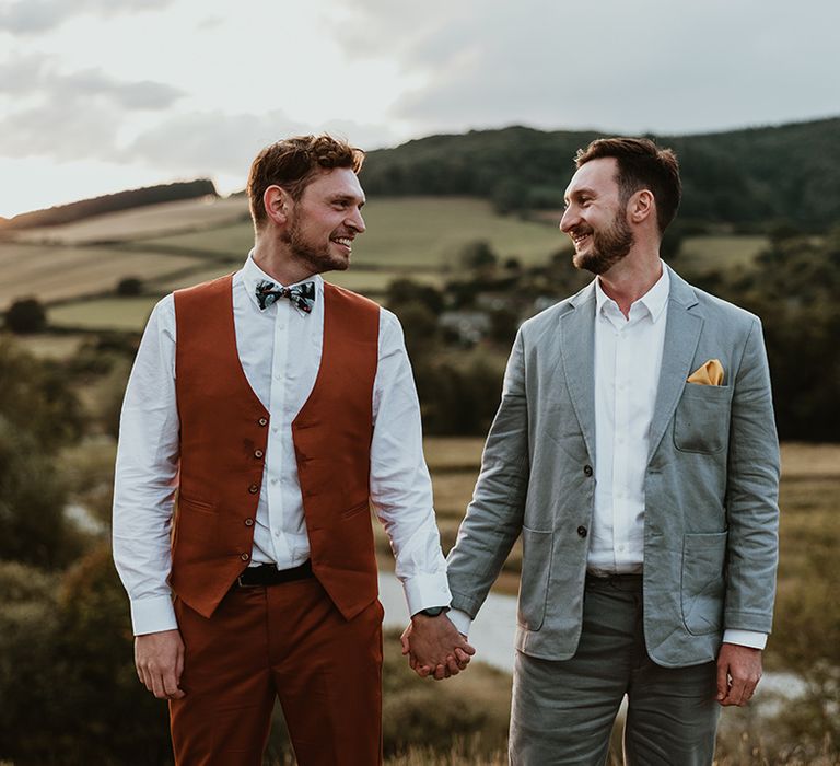 LGBTQIA+ same sex wedding with two grooms holding hands with stunning Welsh view in the background 