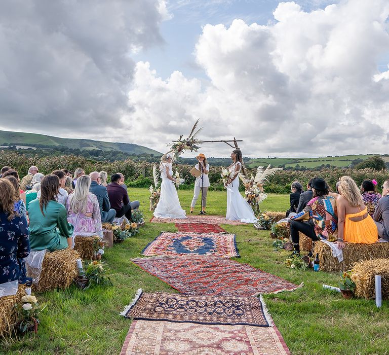 The Party Field outdoor festival wedding with guests sitting on hay bales 