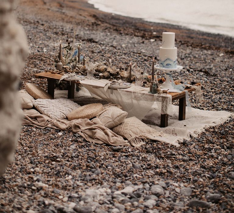 Intimate sweetheart table on the beach with cushions and rugs and grazing board