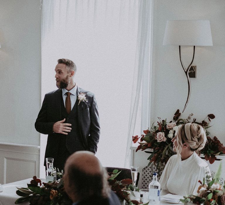 Groom in navy wool suit giving a wedding speech 