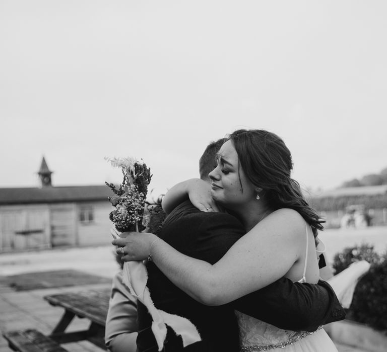 Emotional bride hugging a wedding guest