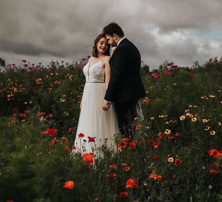 Bride and groom holding hands in wildflower meadow