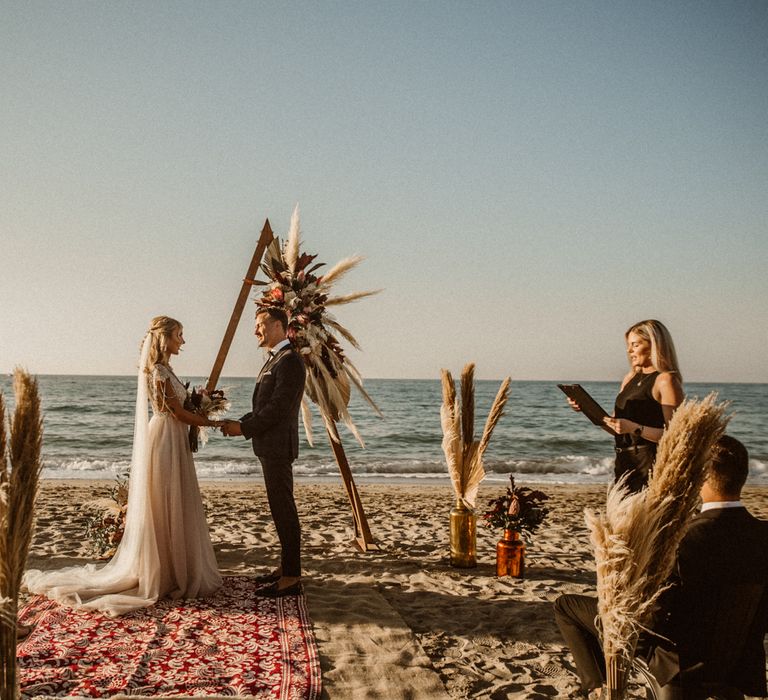 Beach wedding ceremony with rugs for the aisle