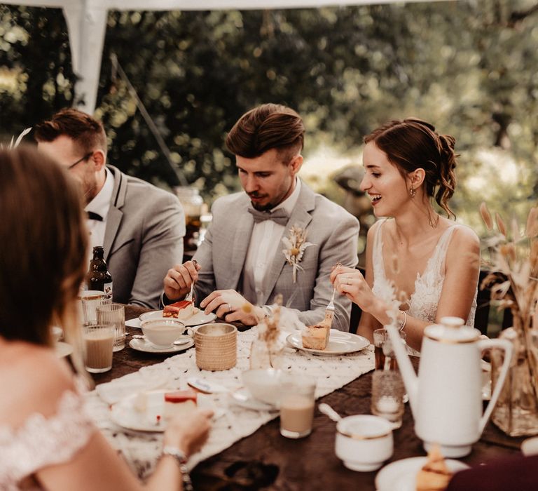 Bride and Groom eating cake at rustic boho wedding