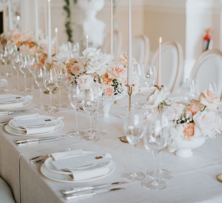 Elegant wedding table decor with gold candlesticks pink taper candles and blue pink and white floral arrangements 