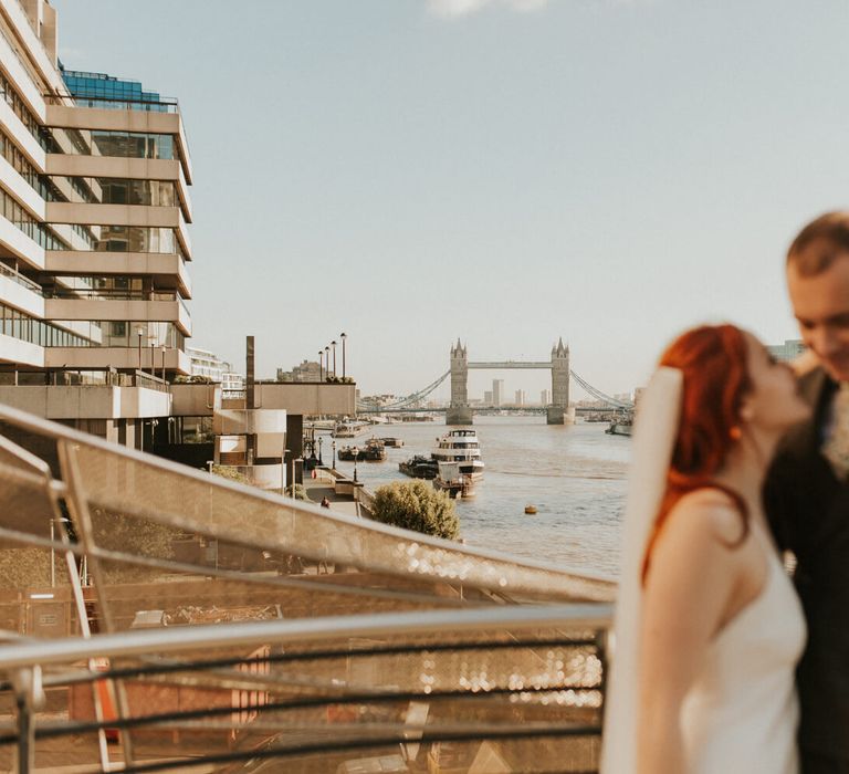 Bride and groom exploring London on their wedding day with a view of London bridge 