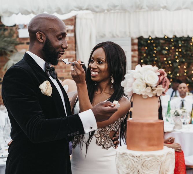 Black bride and groom feeding each other cake at the wedding cake cutting ceremony 