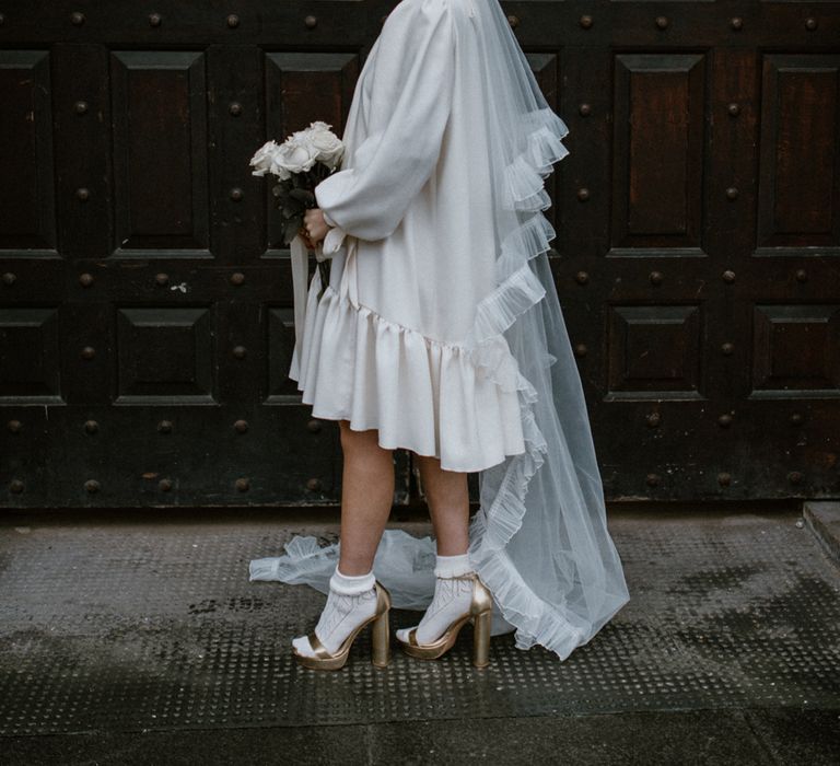 Brunette haired bride wears short ruffled wedding gown with statement gold heels and ankle socks