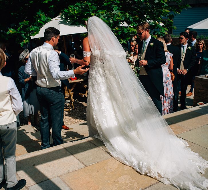 Bride and groom walking into garden wedding reception holding champagne