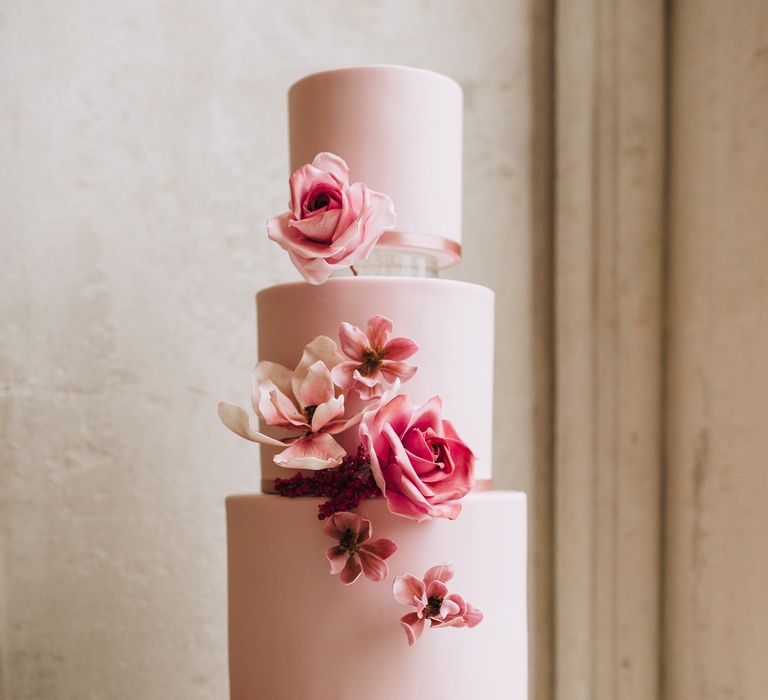 Four tier, pink iced wedding cake with flower design 