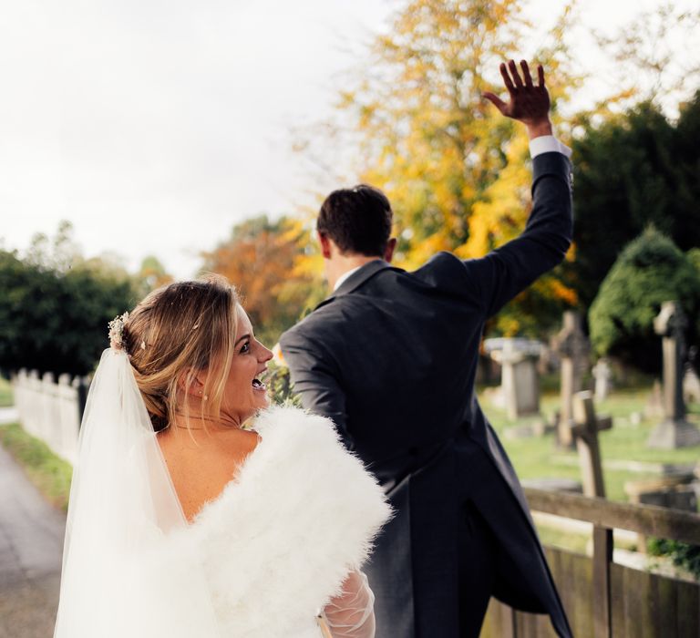 Bride wears white shawl whilst walking with groom outdoors