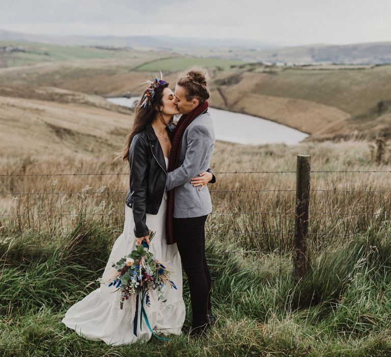 The brides share a kiss in front of an amazing view over the Peak District