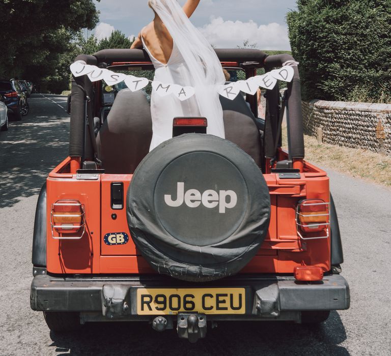 Bride rides in an orange Jeep on the morning of her wedding