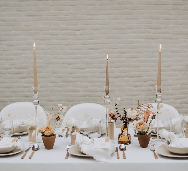 Tapered candles for an intimate all white wedding tablescape with dried flowers and modern seating