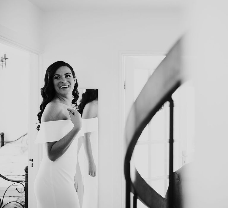 Smiling bride with long curly hair wearing strapless Vagabond wedding dress looks over her shoulder