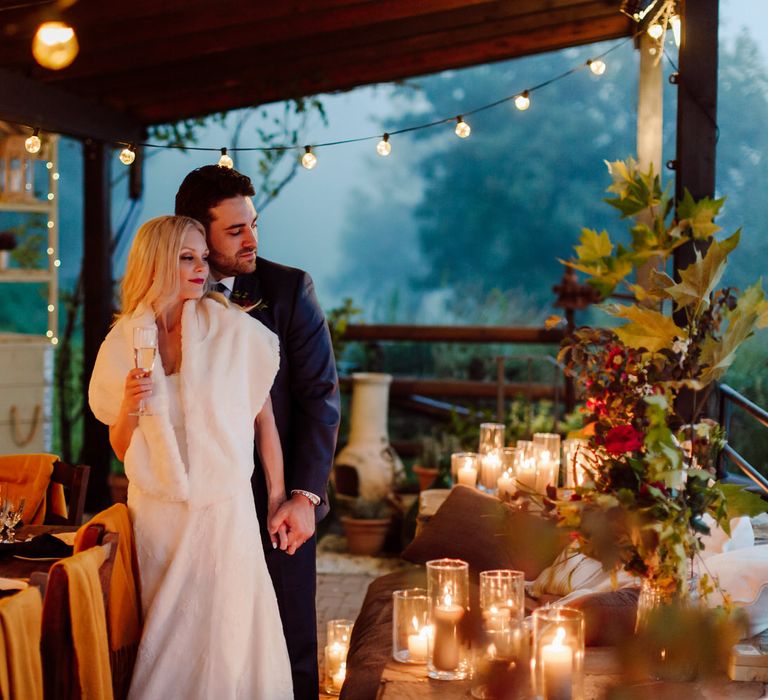 The bride and groom surrounded by lights and candles at their intimate evening wedding dinner in Tuscany