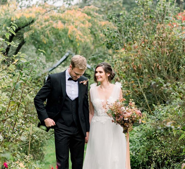 Bride and groom in a tuxedo and tulle wedding dress walking the grounds of Dorfold Hall in Cheshire 