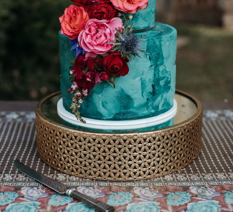 Two tier turquoise wedding cake with pink and red peony decorations