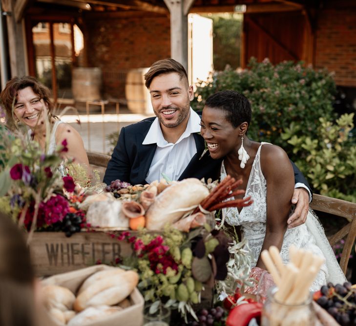 Bride & groom sit at grazing table with rustic vibes