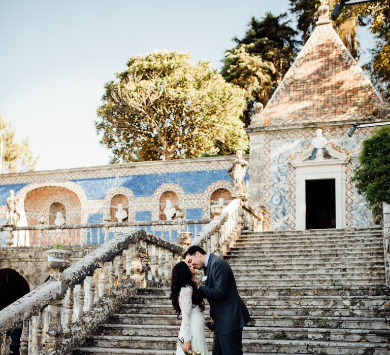 Bride & groom walk up staircase outdoors in front of colourful tiled building