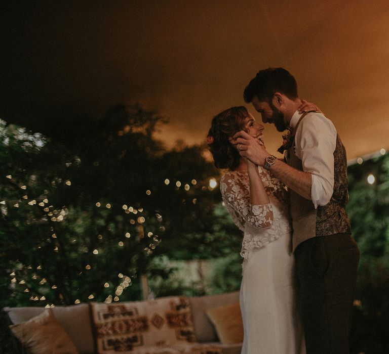 Bride in white Rime Arodaky wedding dress and mesh floral embroidered top dances with groom in white shirt and light brown waistcoat in fairy lit tipi at garden wedding with burnt orange wedding theme