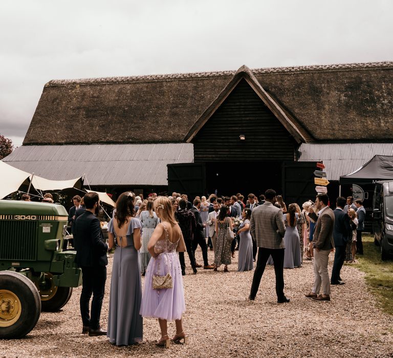 Wedding party gathers outside barn before wedding reception