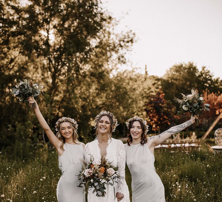 Bride in a boho lace wedding dress and dried flower crown and bridesmaids in grey satin dresses from the high street 