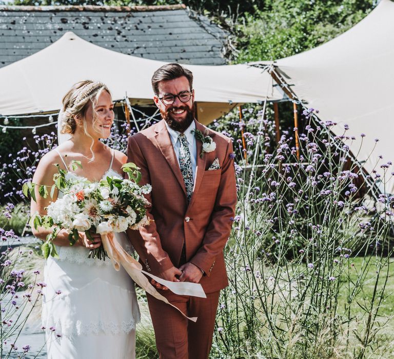 Bride & groom walk down the aisle after their wedding ceremony as wedding guests throw dried confetti 