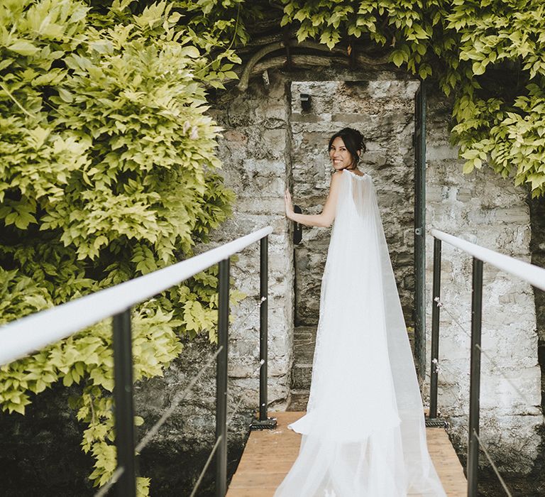 Bride wears gossamer cape for bespoke tulle and lace wedding gown