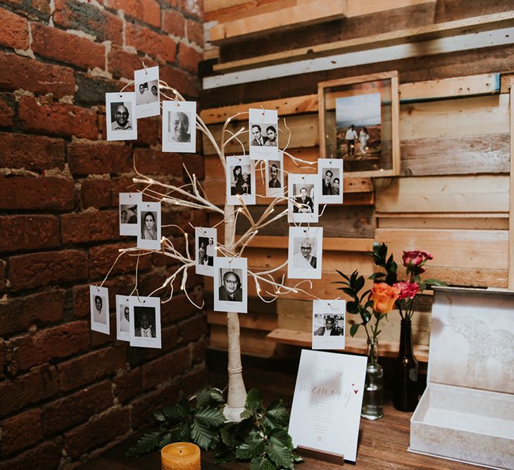 Polaroid photos hang from a decorative tree at an Indian British wedding.