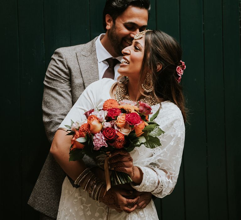 A bride and groom embrace for a wedding portrait at their Indian British wedding. 