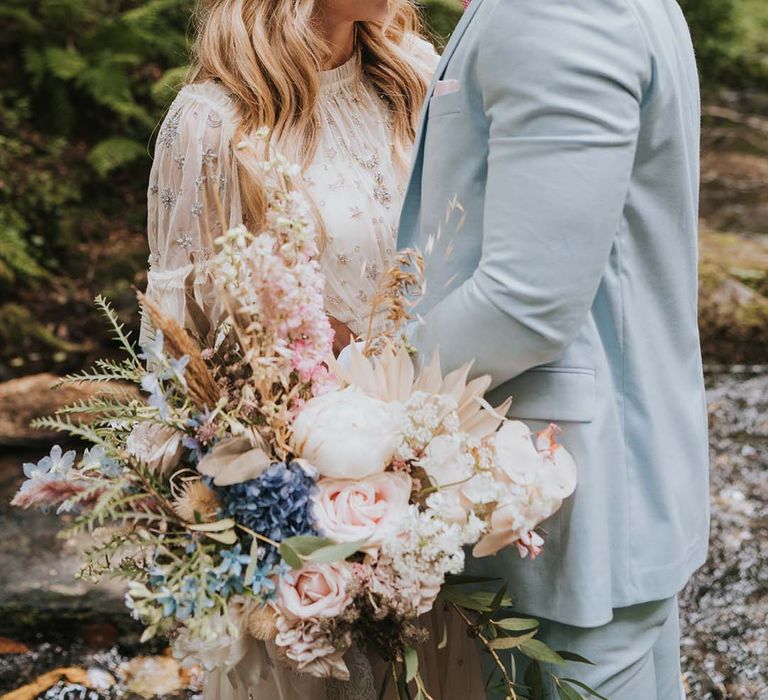 Bride & groom look at one another on their wedding day in front of waterfall 