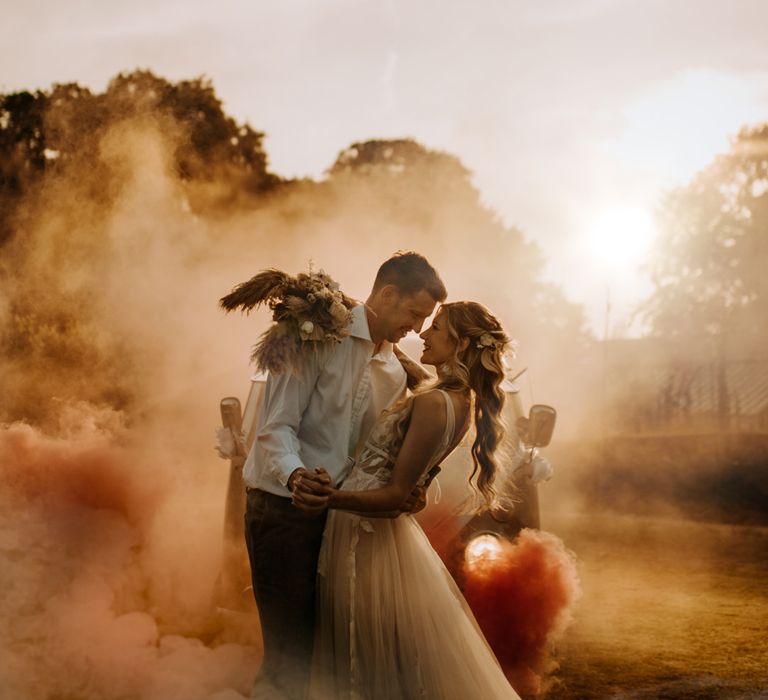 Golden hour couples portrait with a white smoke bomb blowing in the background 