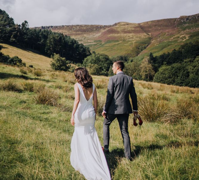 Bride and groom walk away from camera over rolling hills