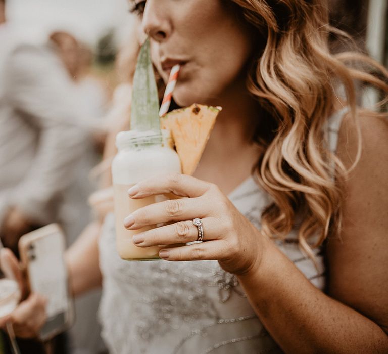 Bridesmaid sips cocktail outdoors